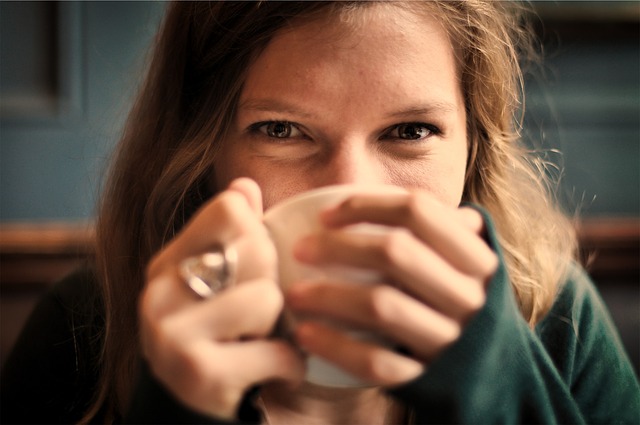 コーヒーカップを持ちながら微笑む女性