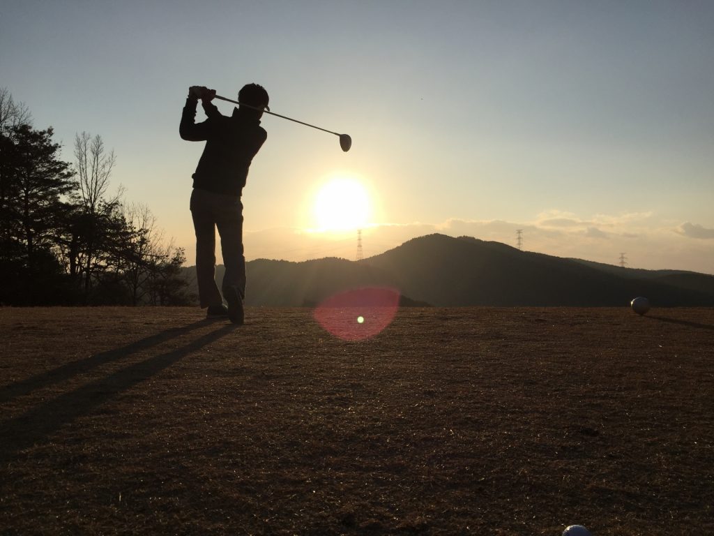 夕日とゴルフをする人